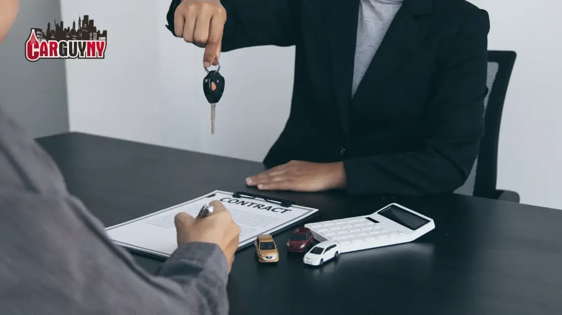Person signing a car contract at a table with miniature cars, a calculator, and receiving car keys.